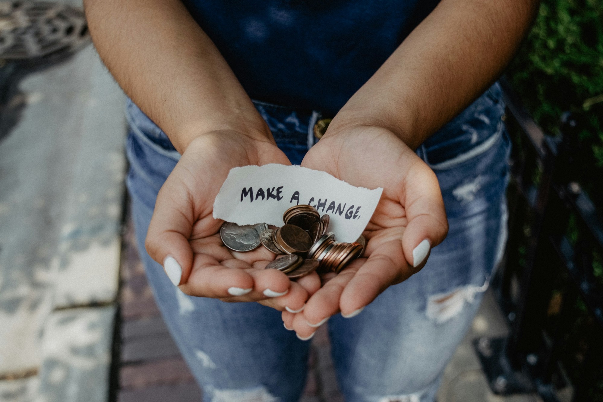 Open hands holding coins and a note that says make a change